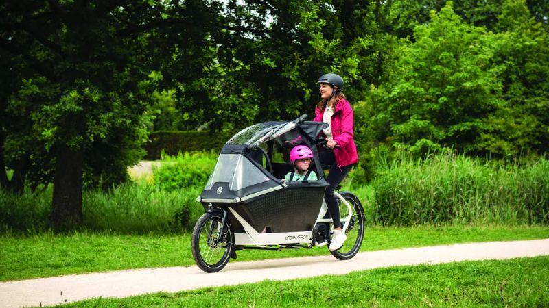 Moeder met kind op bakfiets in de regen 