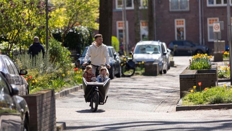 Vader met twee kinderen in bakfiets door de straten 