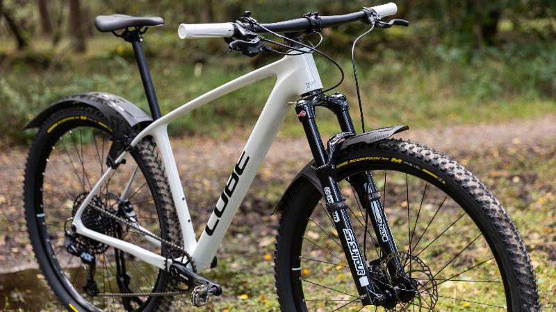 Witte cube mountainbike met spatborden.